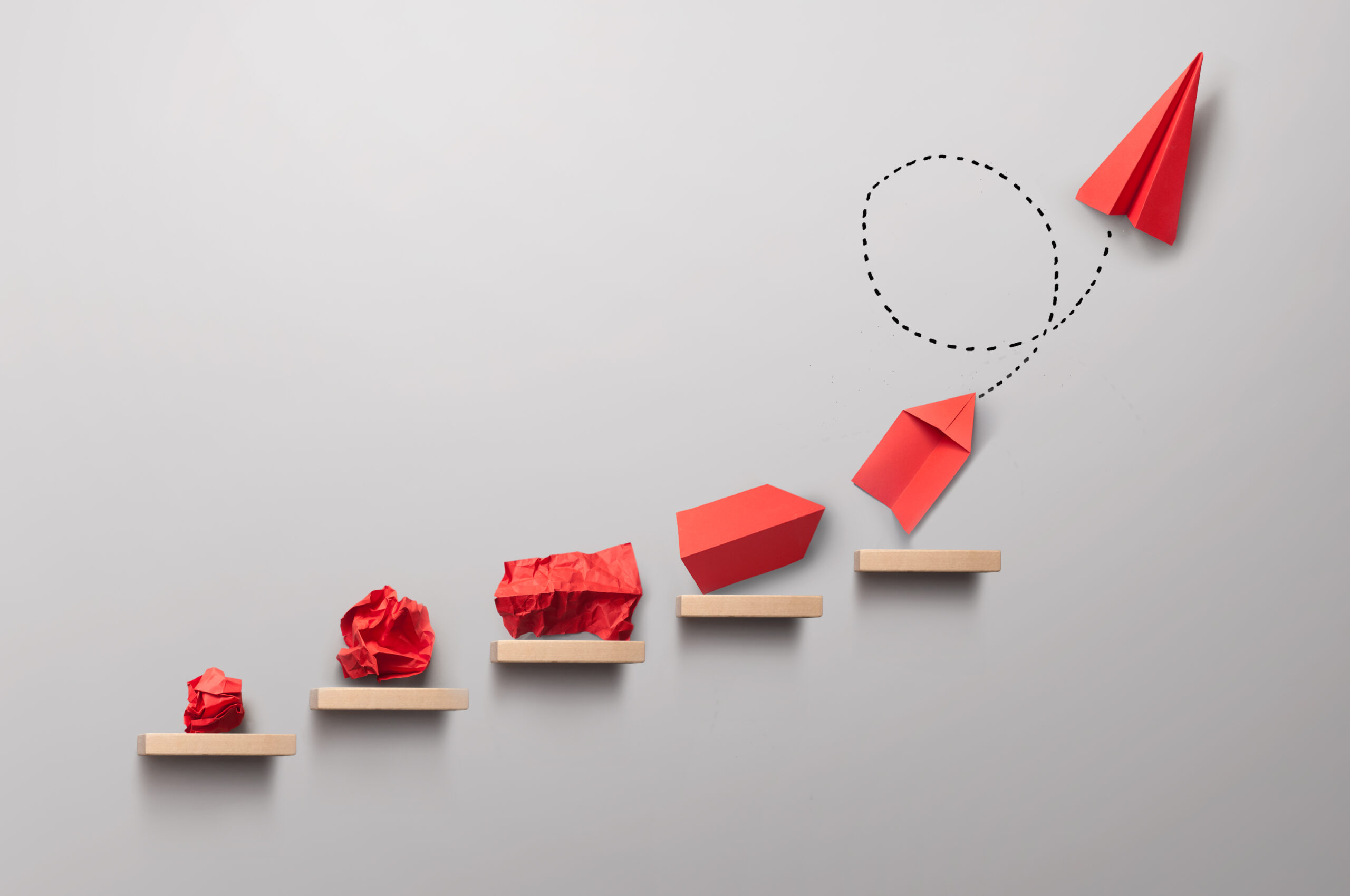 Wooden steps with different stages of making a paper airplane