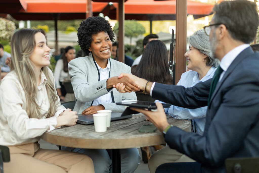 Professionals shake hands during a friendly meeting, showing face-to-face marketing in action.